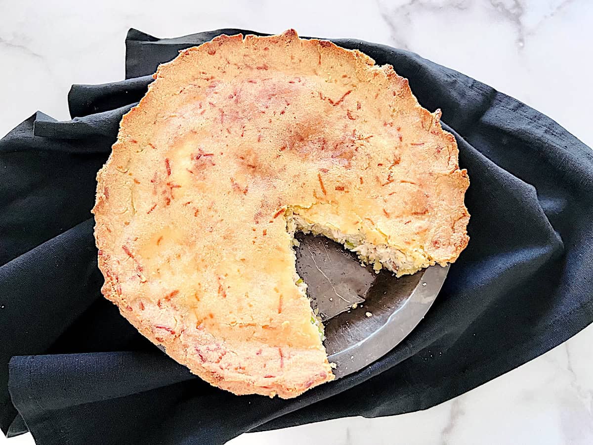 A whole keto pot pie with a slice cut out showing the flaky crust and chicken filling.