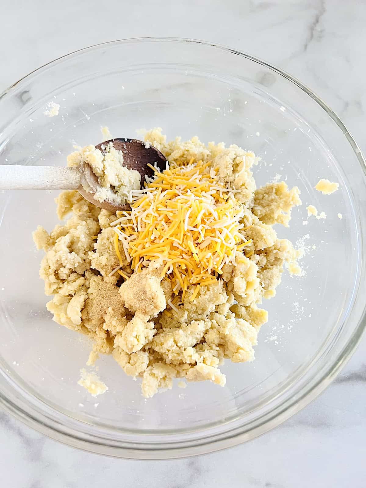Adding shredded cheese to almond flour dough.