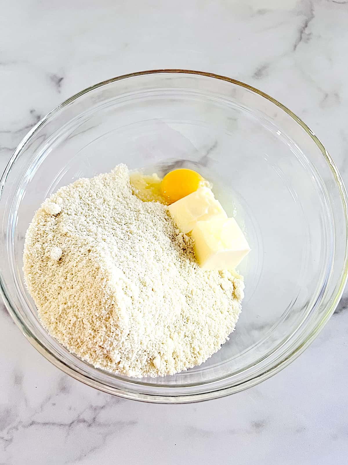 Bowl with almond flour salted butter and egg.