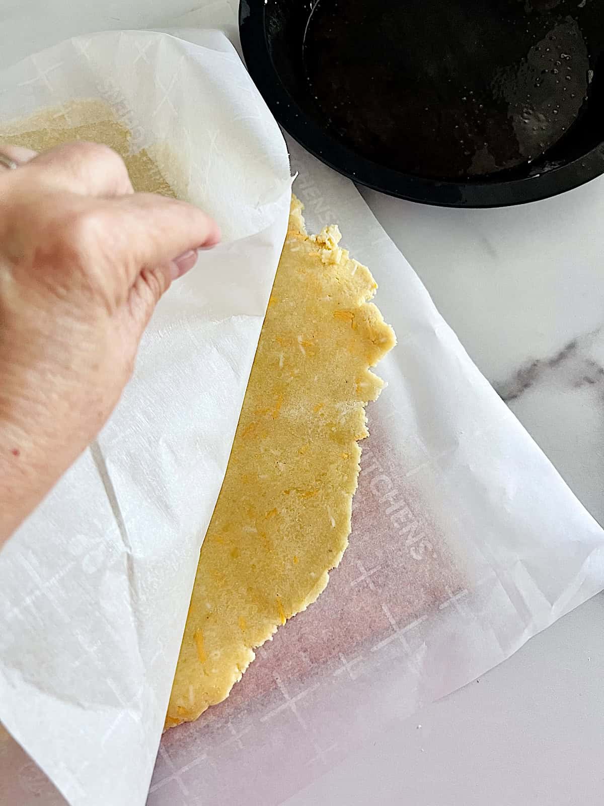 Peeling back the parchment on the rolled and chilled keto pie crust.