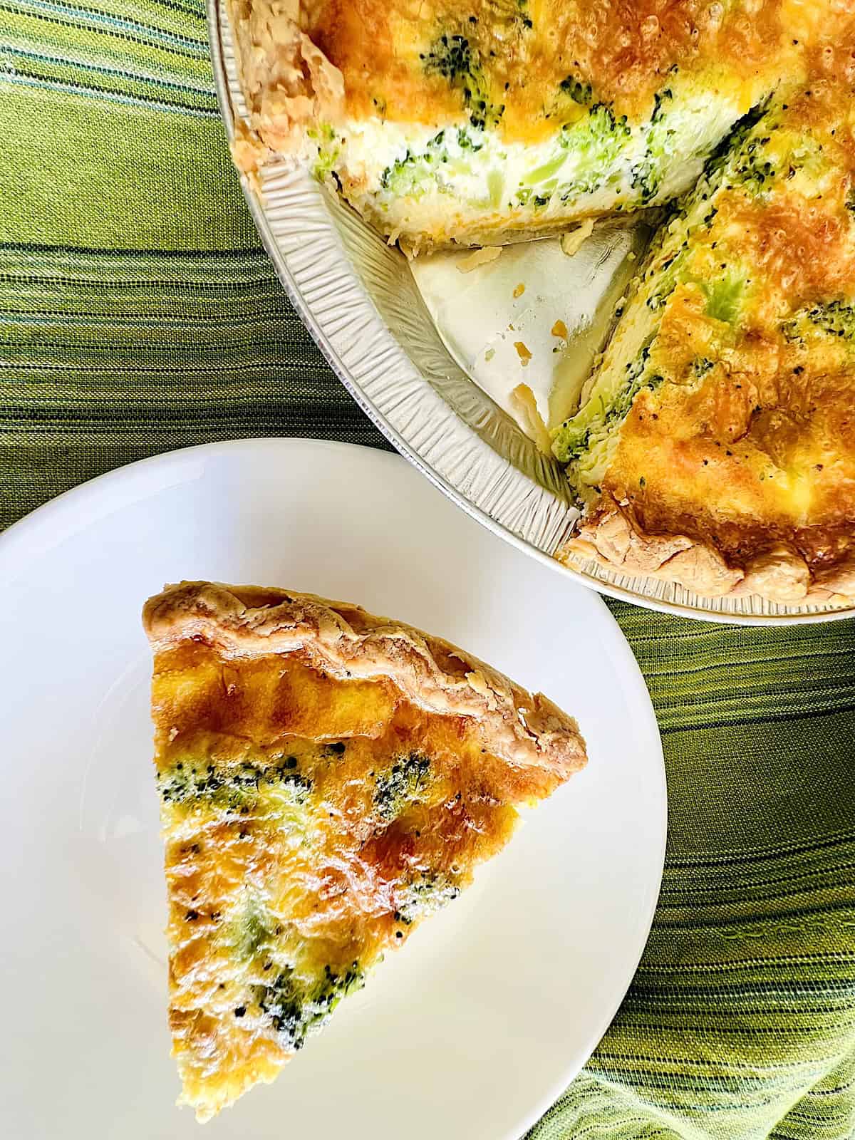 Broccoli Cheese Quiche Best Recipe slice on a plate next to full egg veggie custard in pie crust.