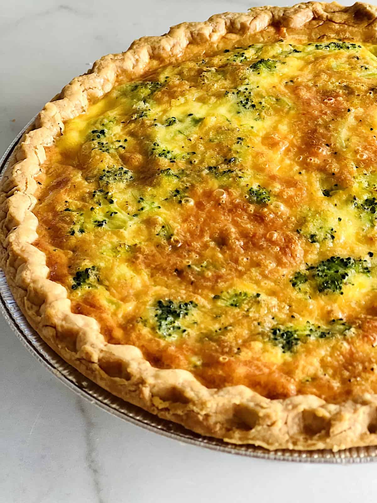 Broccoli Cheese Quiche Resting after baking showing golden crust and bubbly cheese topping.