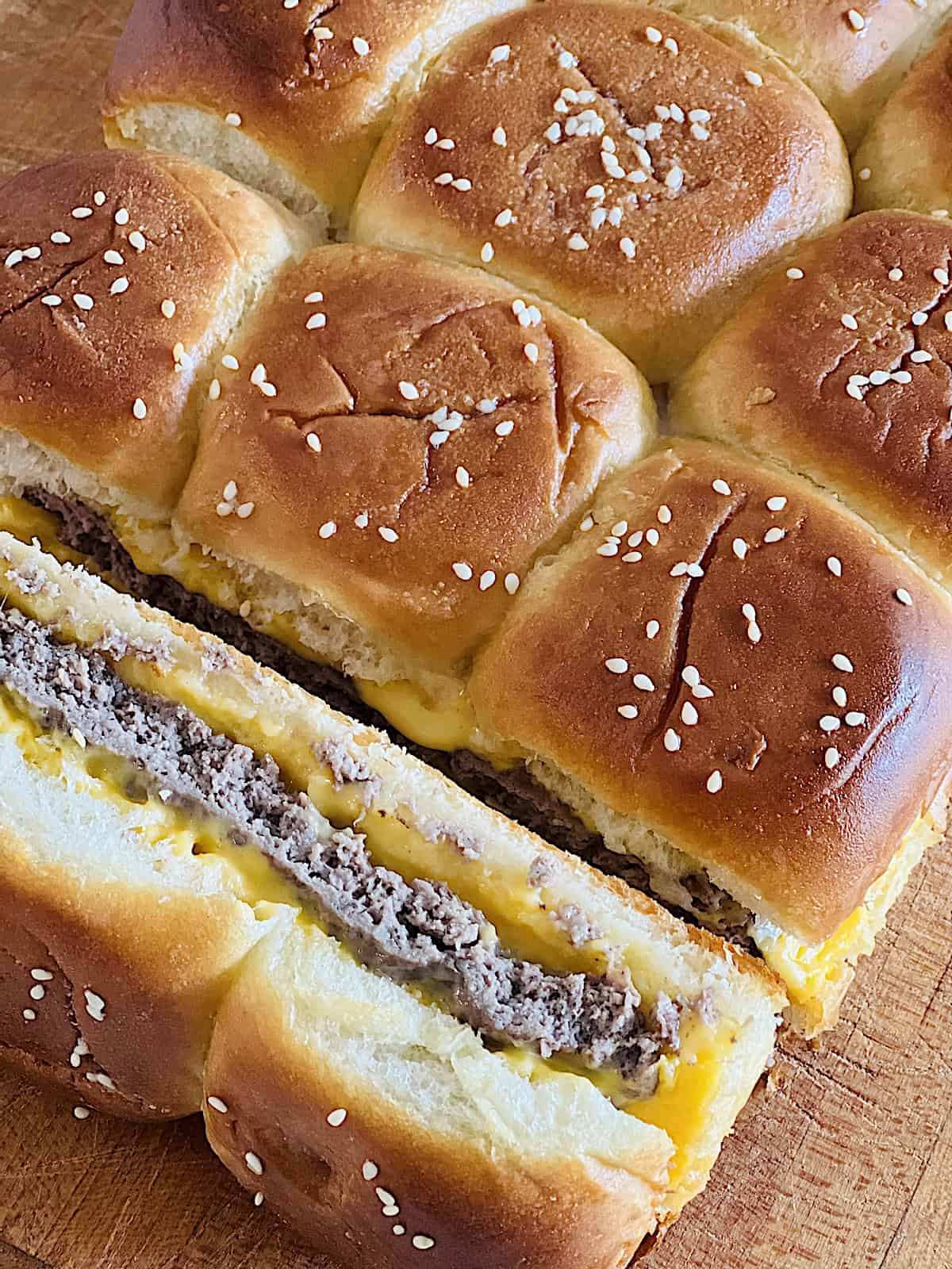 Cheeseburger Sliders Closeup Sliced to show burger meat and cheese layer.