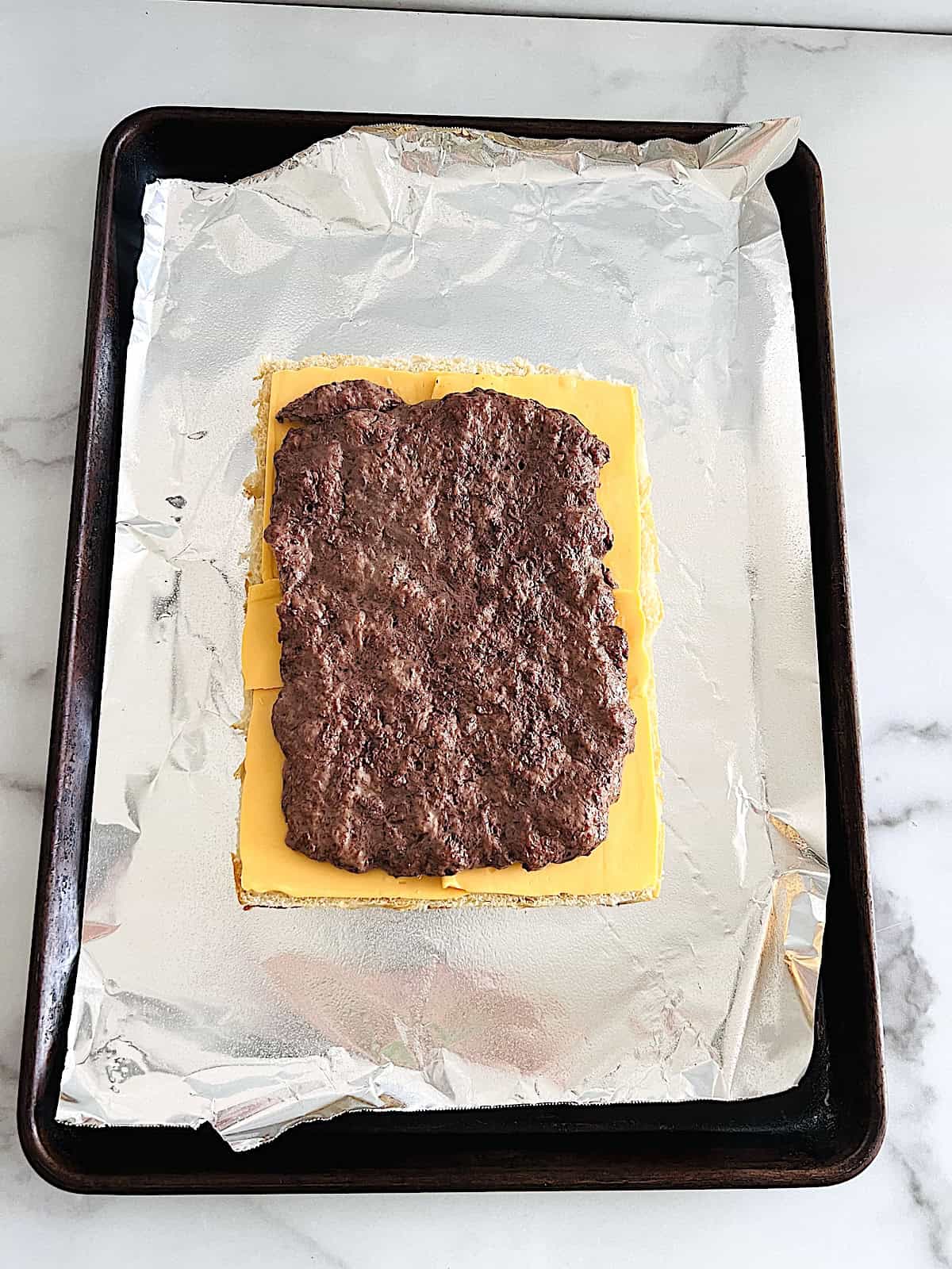Cheeseburger Sliders Cooked layer of meat on top of bottom bun and american cheese layer.