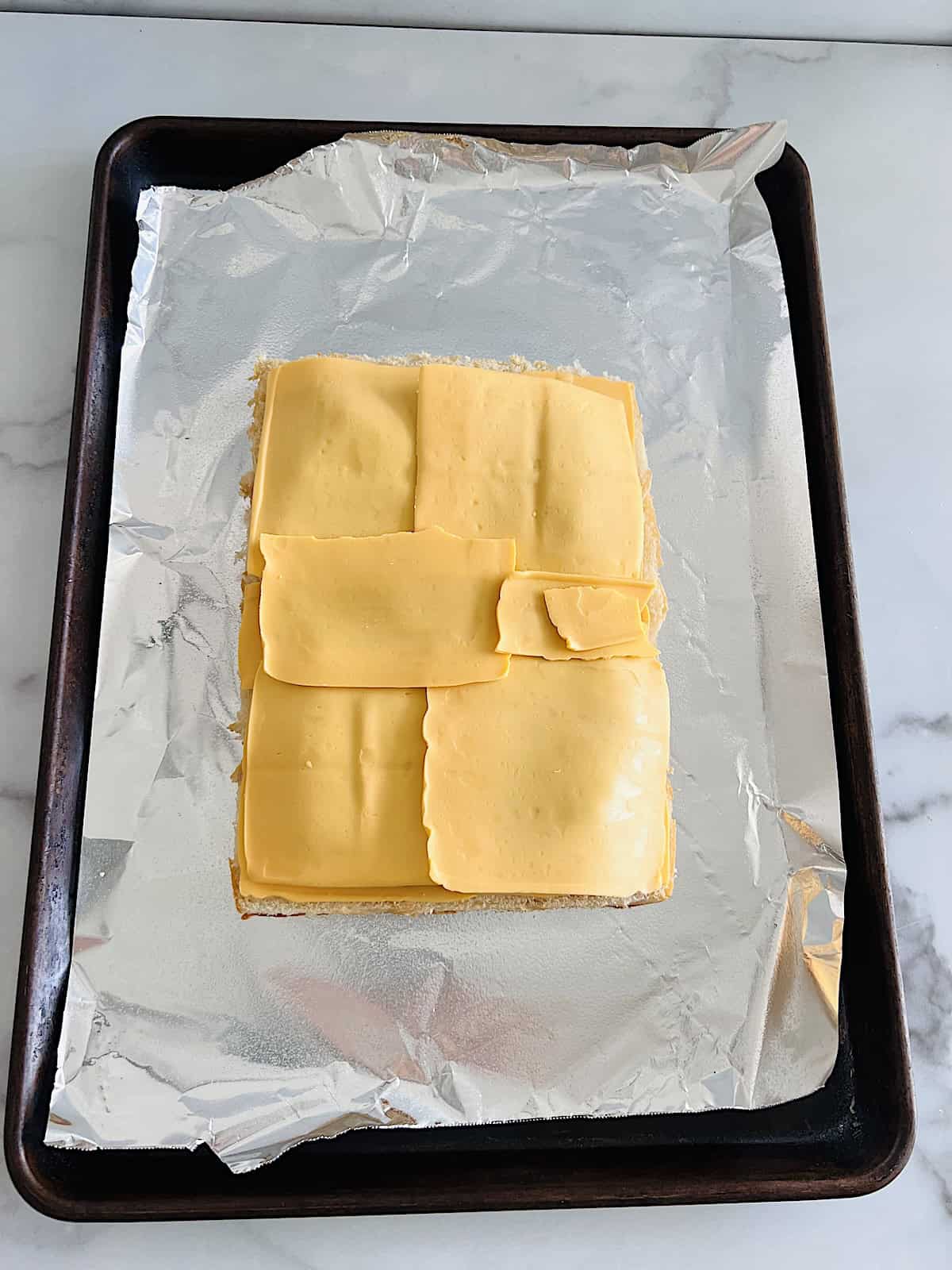Final layer of cheese over slab of cooked ground beef.