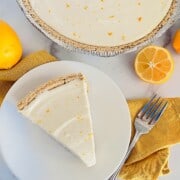 No-Bake Lemon Cheesecake Pie slice and plated next to the full creamy pie in graham cracker crust.