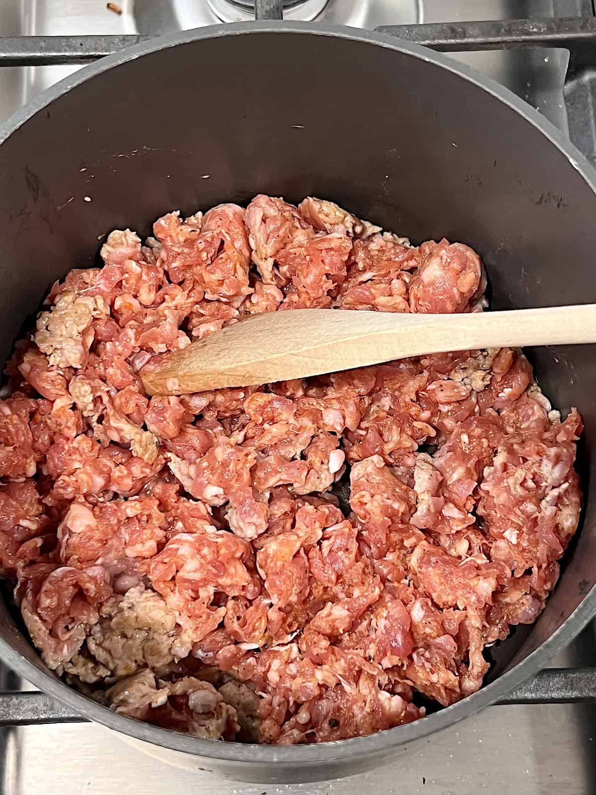 Pot with ground italian sausage broken into small pieces to cook.