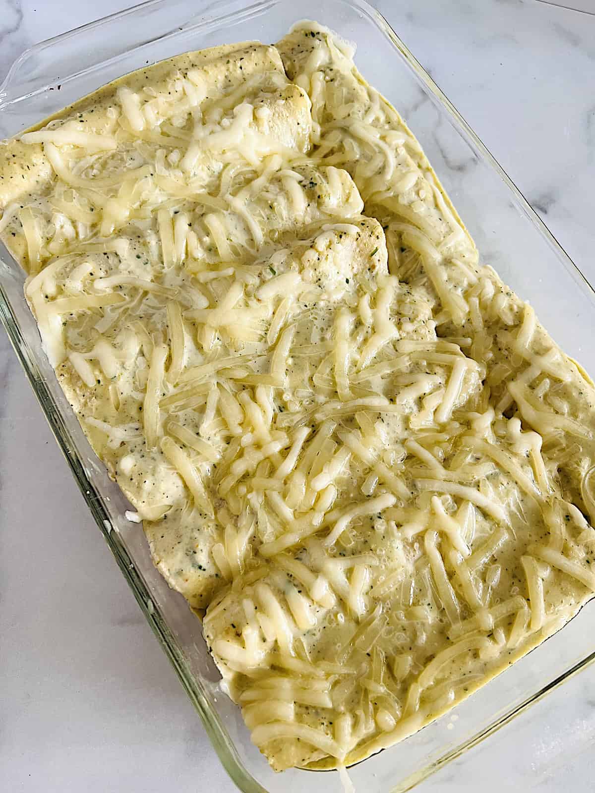 Enchiladas Suizas Baked in green salsa cream sauce topped in cheese.