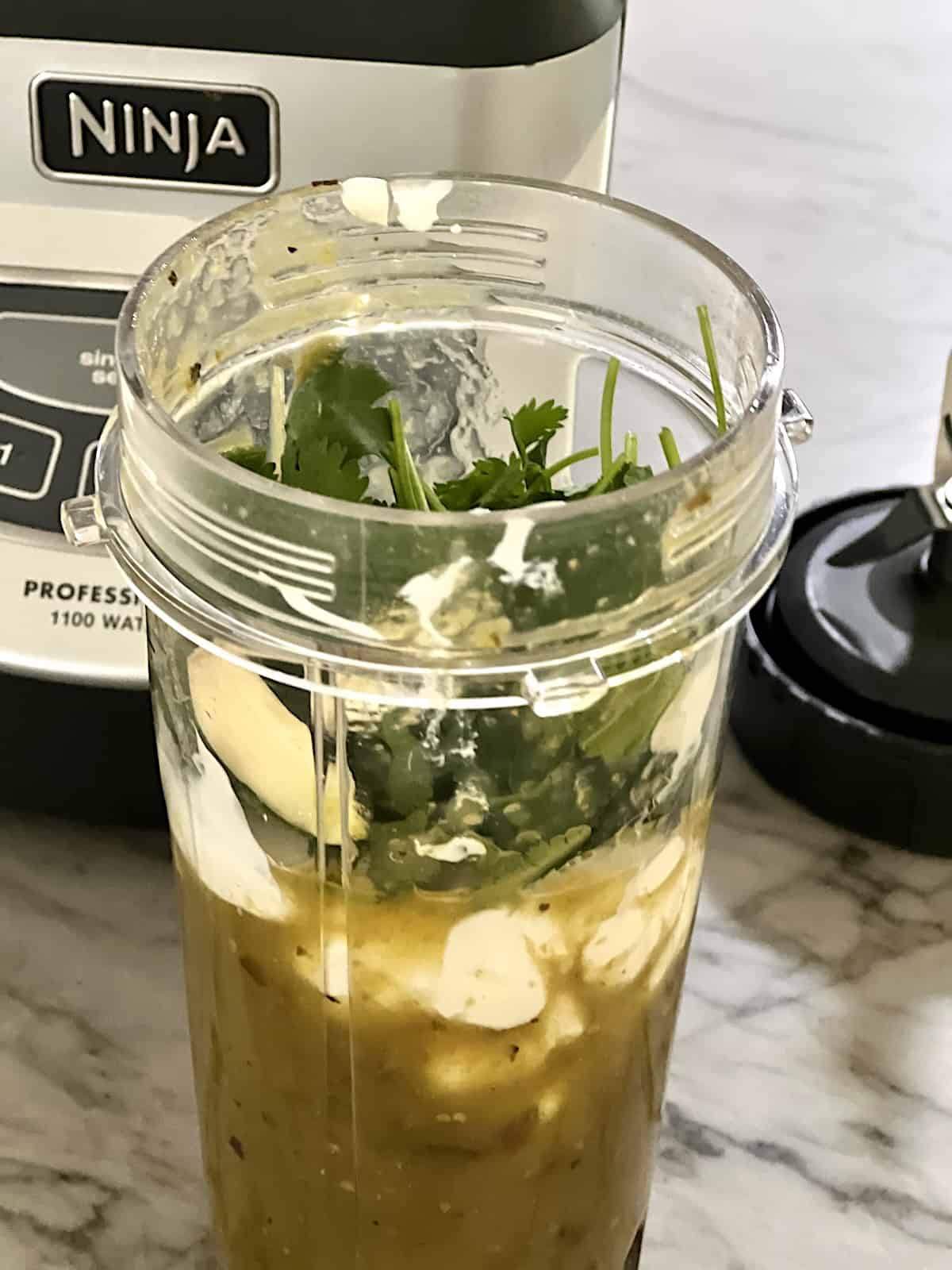 Blender cup with salsa verde Mexican crema cilantro and garlic.