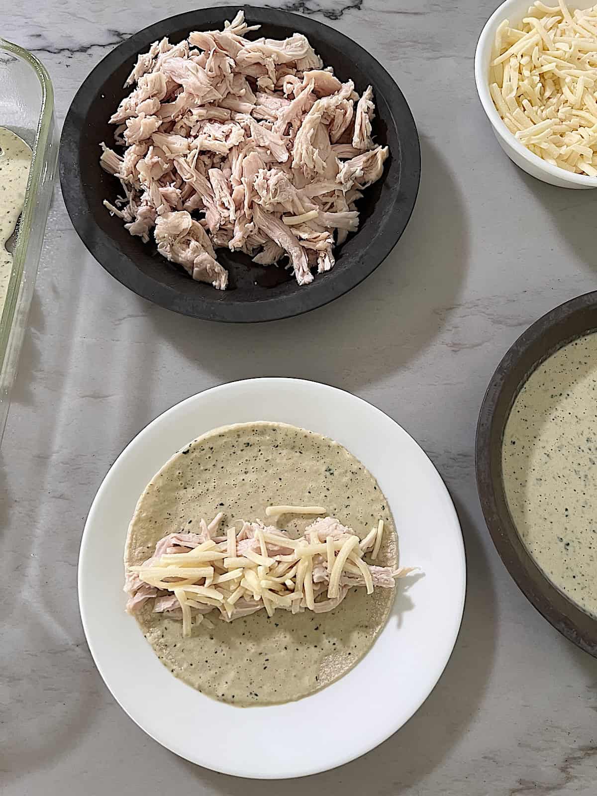 Showing how to roll a corn tortilla with shredded chicken and cheese.