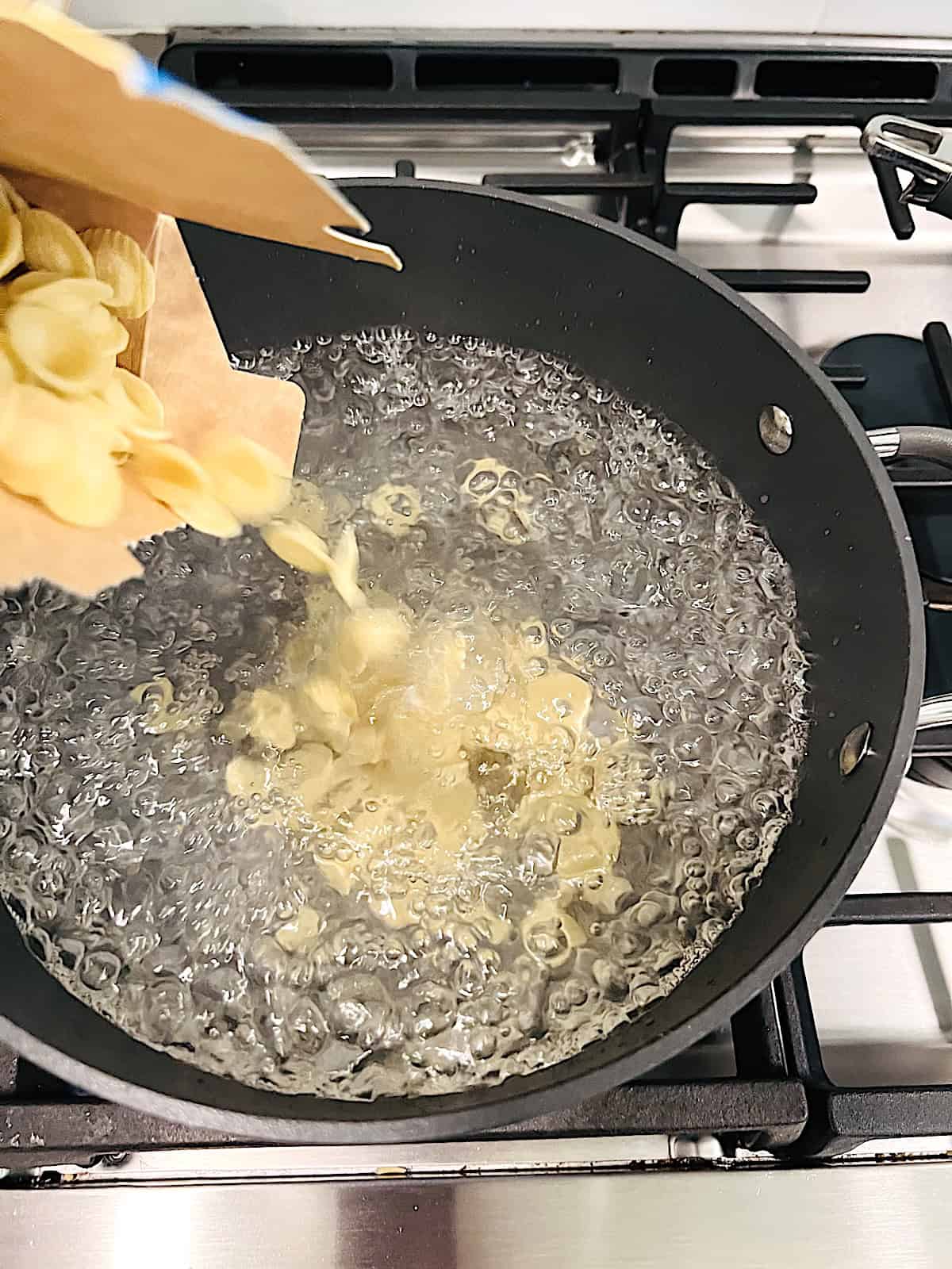 Adding dry pasta to boiling water.