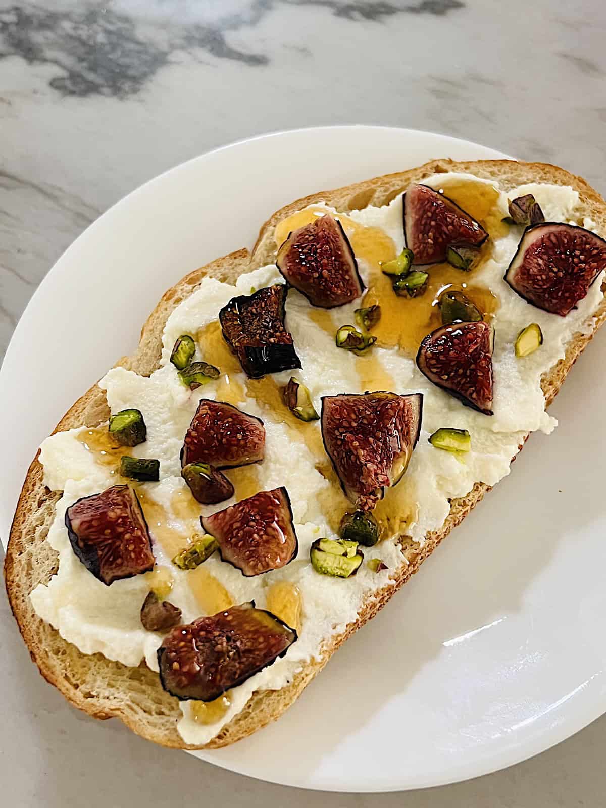 Ricotta Fig Toast Hot honey on top of pistachios figs and ricotta on toast.