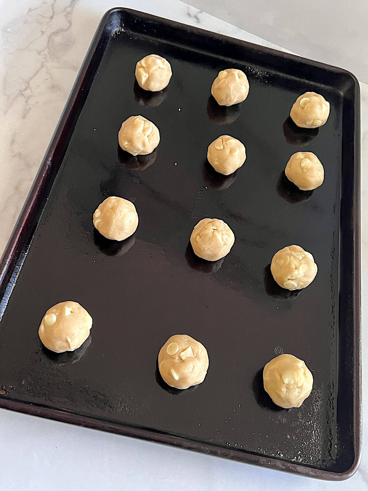 Rolled cookie dough balls on a baking sheet.