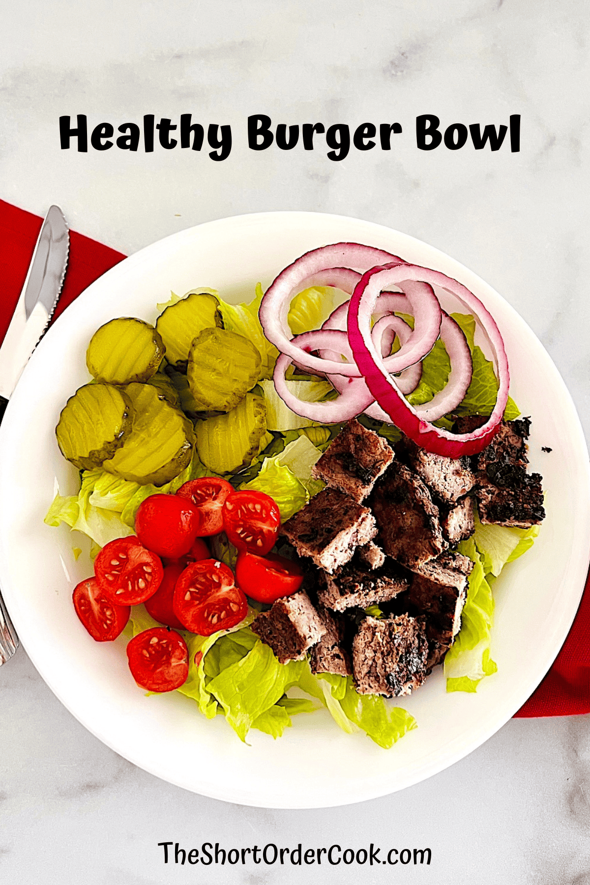 Bowl with lettuce and diced cooked ground beef patty, vegetables, & dressing on the side.