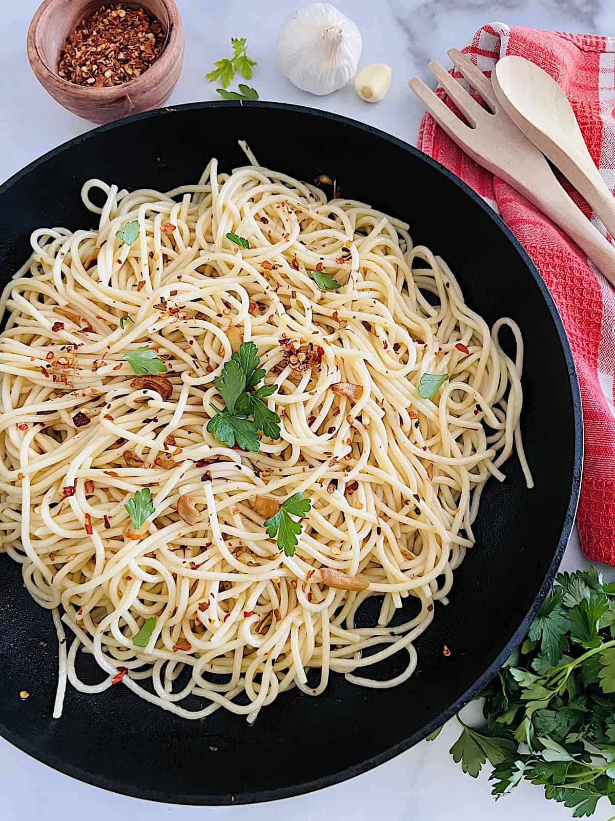 Spaghetti Aglio Olio e Peperoncino Best authentic recipe with garlic olive oil and chili flakes in a pan with parsley.