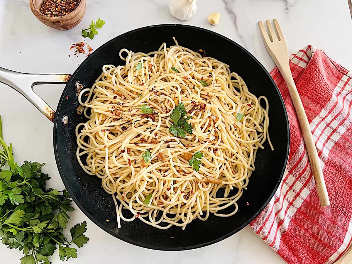Spaghetti Aglio Olio e Peperoncino easy authentic recipe with garlic olive oil and chili flakes in a pan with parsley