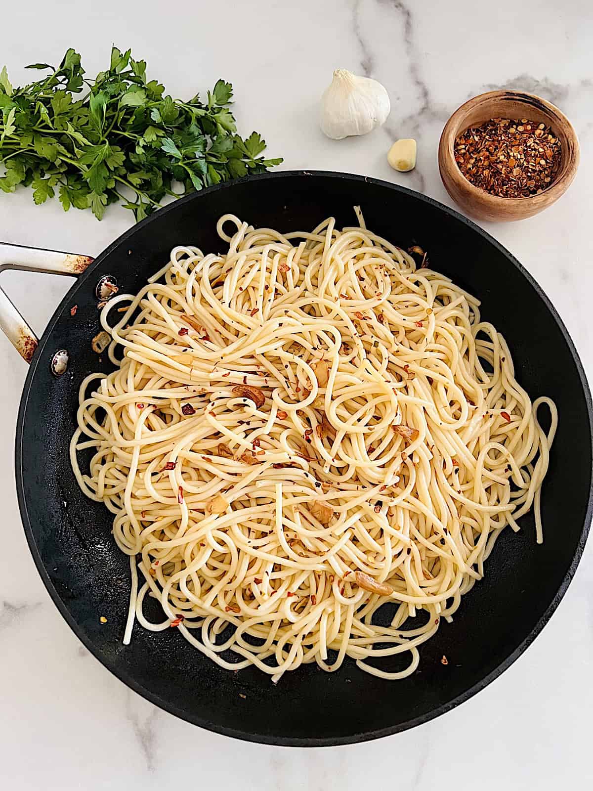 Spaghetti Aglio Olio e Peperoncino Ready to serve with parsley and chili flakes to the side for topping.