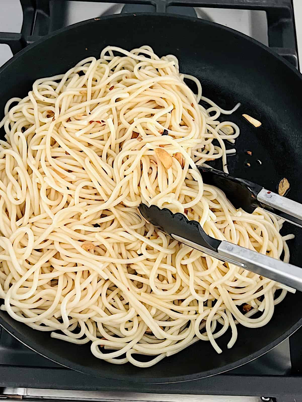 Spaghetti Aglio Olio e Peperoncino tossing pasta in sauce.