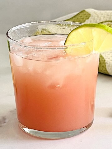 Glass of guavarita, a pink guava margarita with a salted rim served over ice.