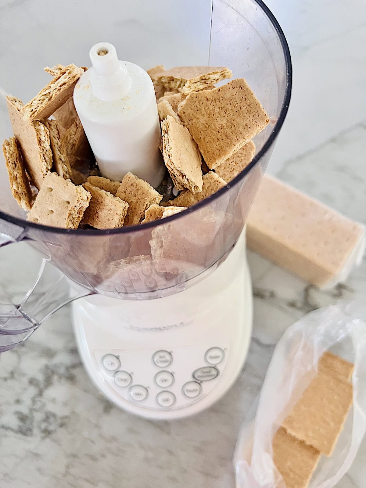 Broken graham crackers pieces in food processor.