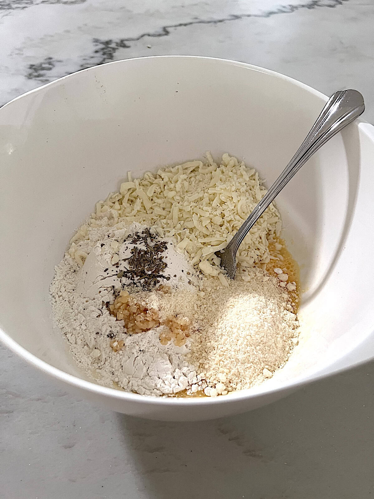 Cheese eggs flour spices in bowl.