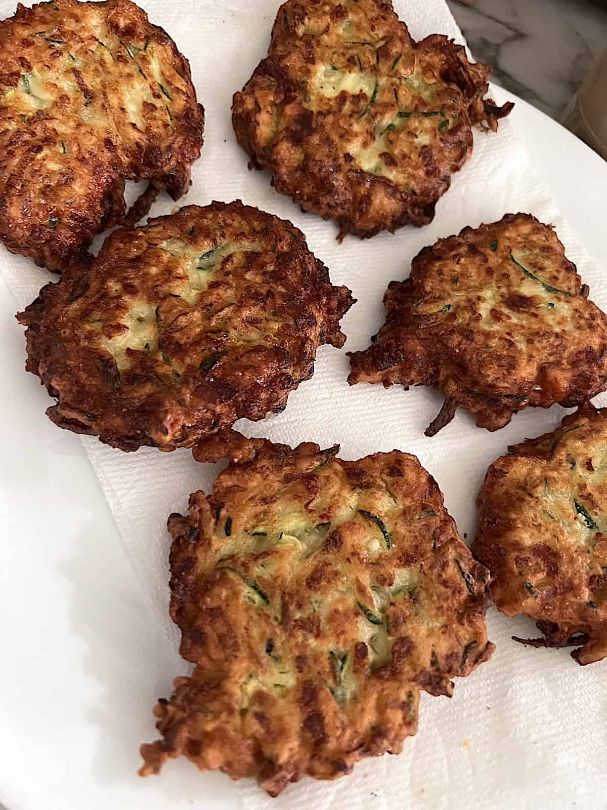 Zucchini Fritters Draining on paper towels after frying.