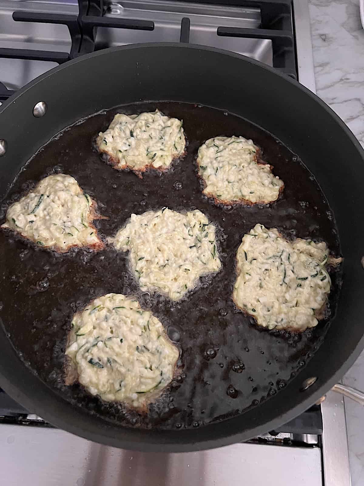 Zucchini Fritters Frying batter in skillet with oil first side.