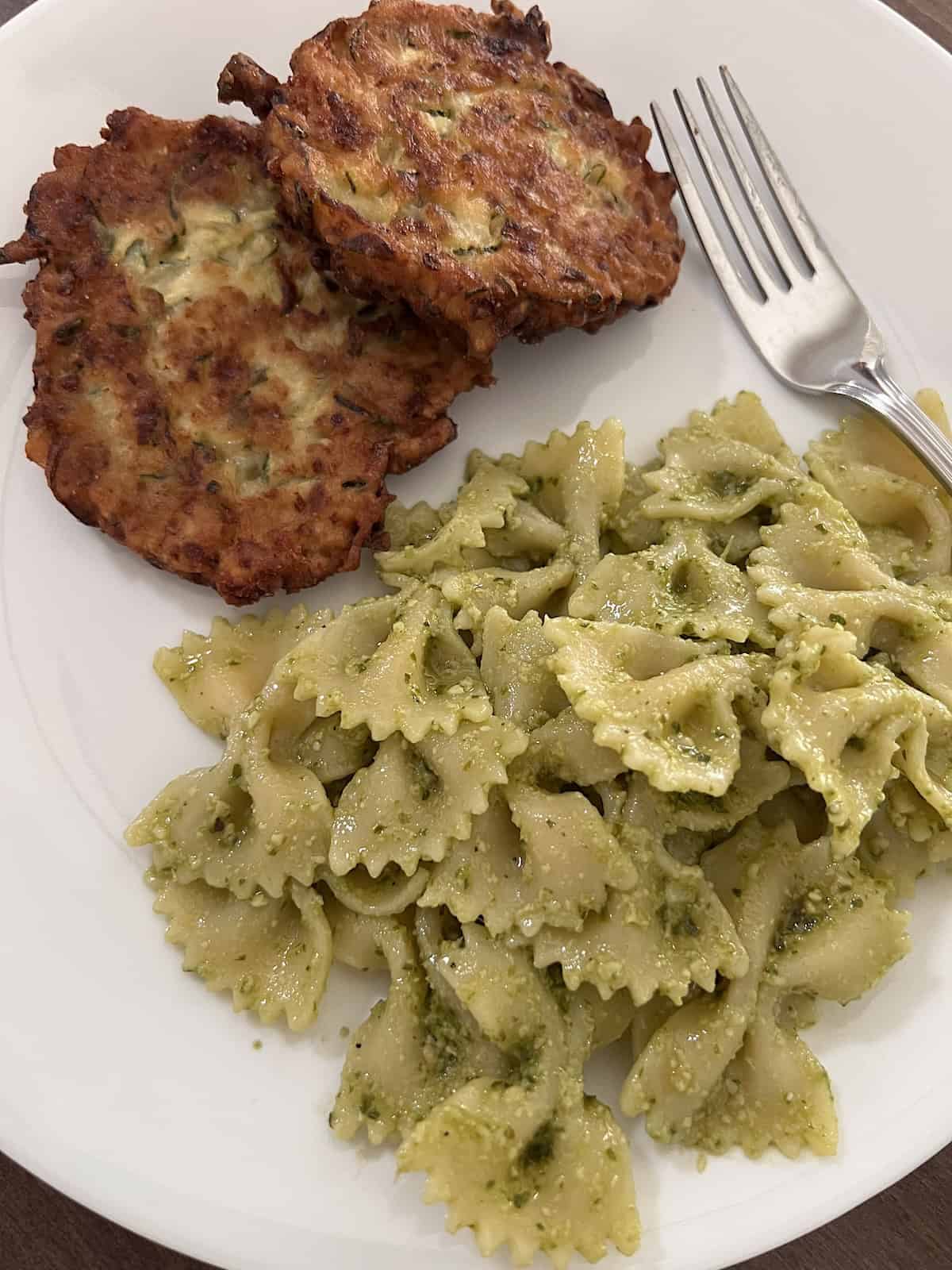 Zucchini Fritters Served on plate with pesto pasta.