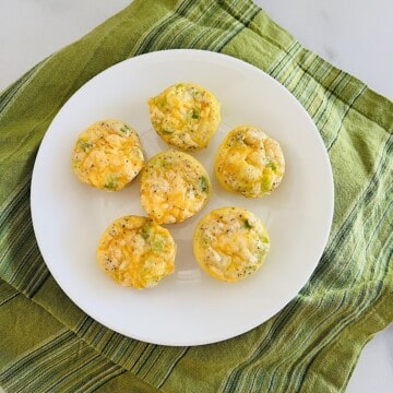 Plate with mini egg bites fresh baked and ready to eat with cheese, ham, & onions.