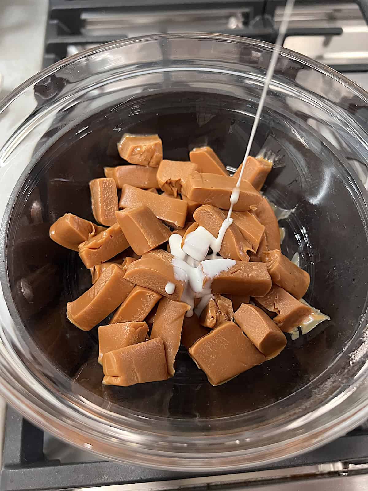 Bowl over pot of water as a double boiler with diced caramel loaf and cream.