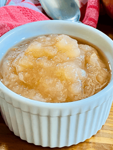 White bowl of homemade apple sauce made with fresh fall fruit in a Slow Cooker .