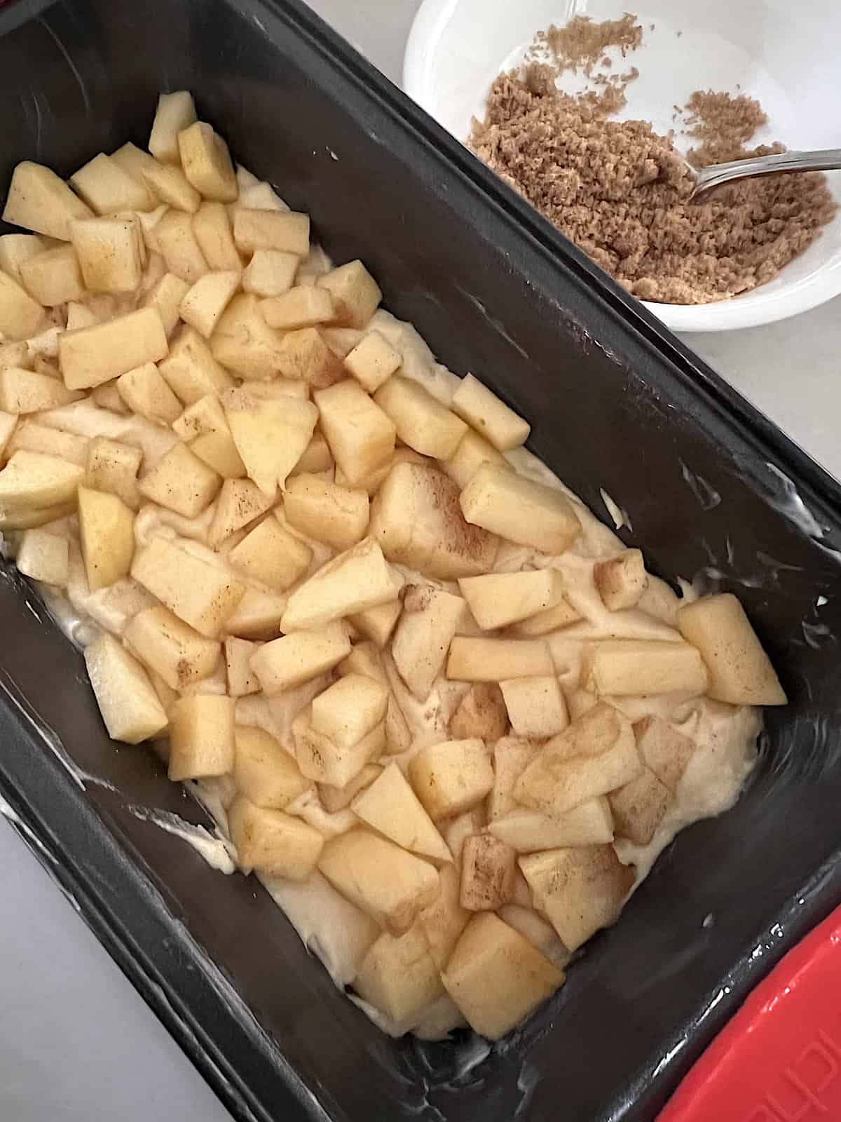 Apple Fritter Bread with Maple Glaze Cake batter topped with diced apples.