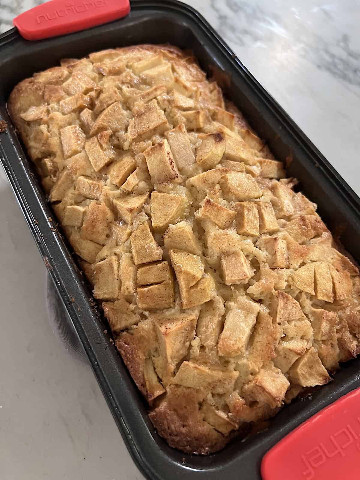 Apple Fritter Bread with Maple Glaze Fresh baked in a loaf pan resting out of the oven.