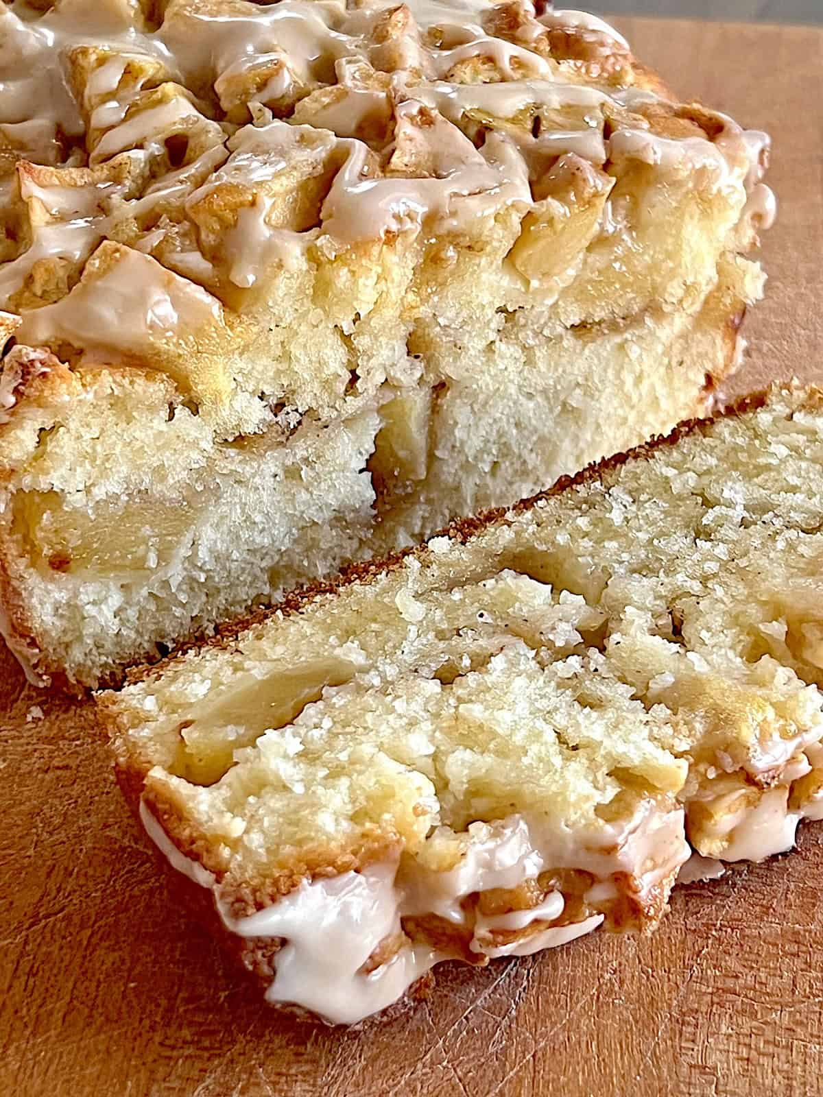 Apple Fritter Bread with Maple Glaze Sliced on a cutting board showing layers of cinnamon apples inside.
