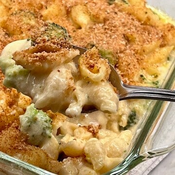 Spooning a big serving of baked mac and cheese with broccoli and chicken.