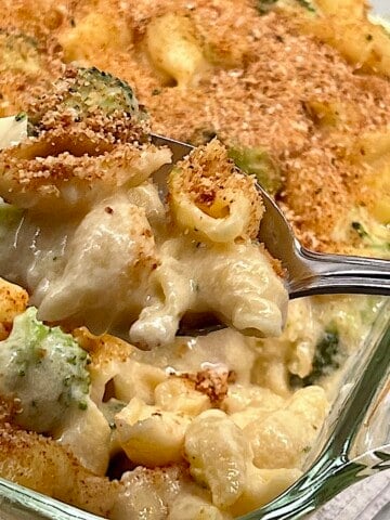 Spooning a big serving of baked mac and cheese with broccoli and chicken.