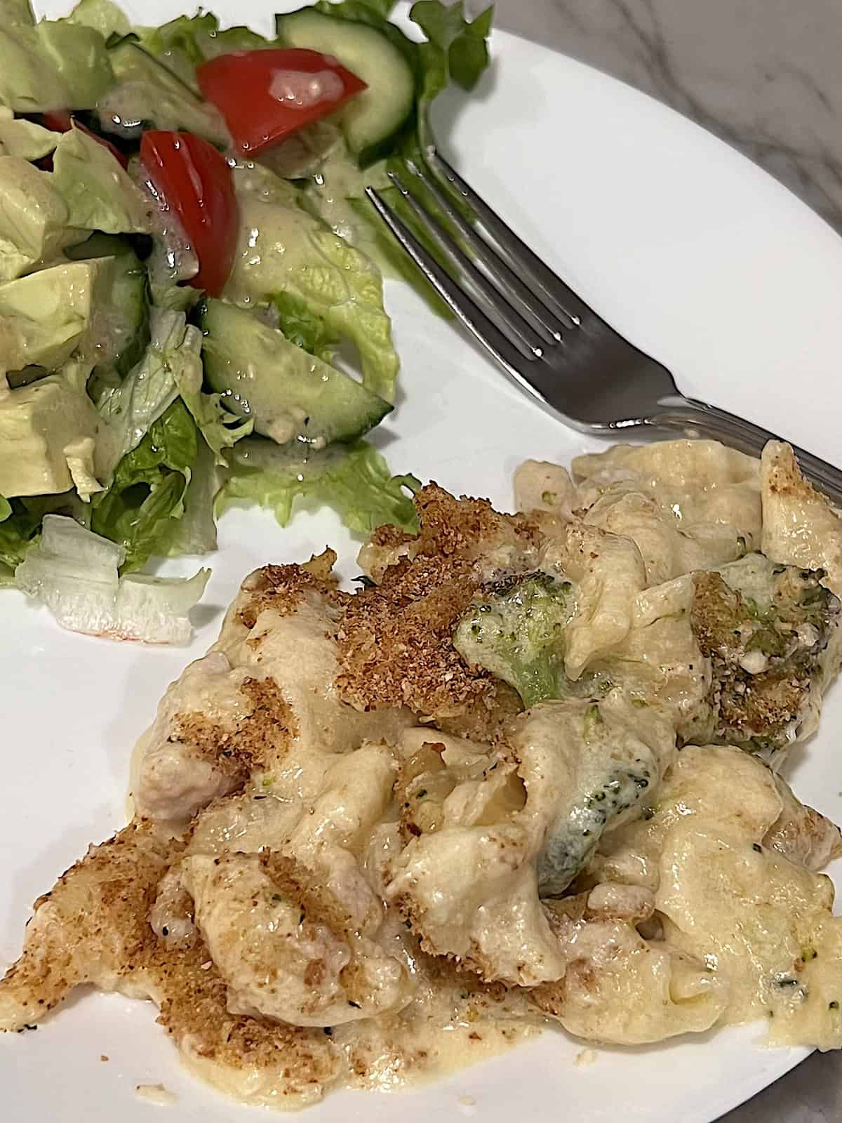 Chicken Broccoli Mac & Cheese on a plate with a green salad.